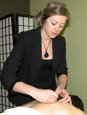 Kelli Irvine NP examines the placement of acupuncture needles in her client’s back. Image by Marlene Eisner.
